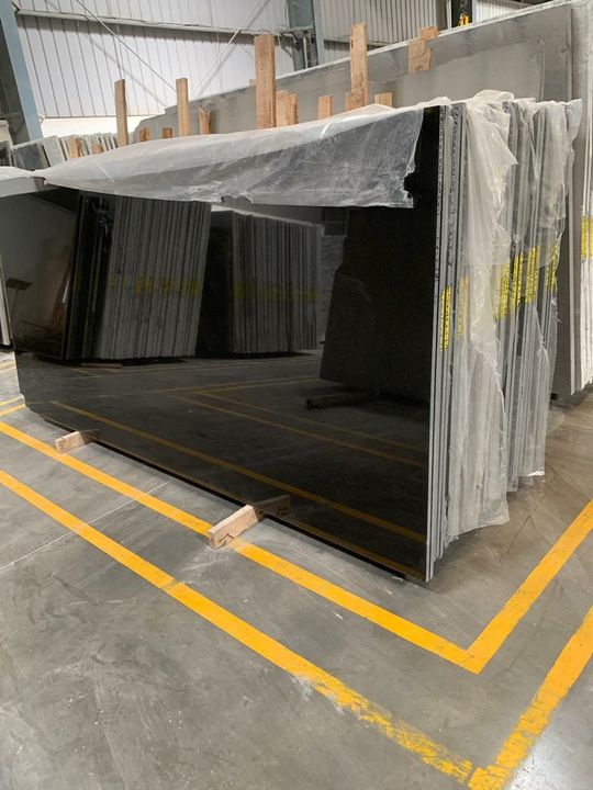 Stack of polished jet-black granite slabs in a warehouse
