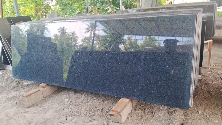 Polished dark blue-grey granite slabs standing outdoors