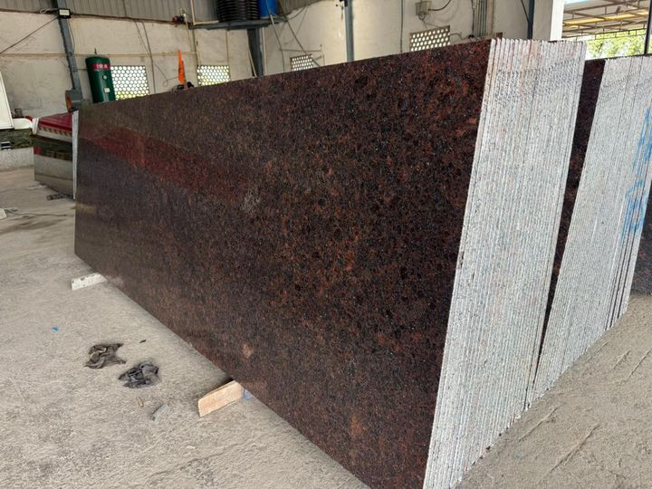 Red-brown granite slab with dark crystals and a lappato finish