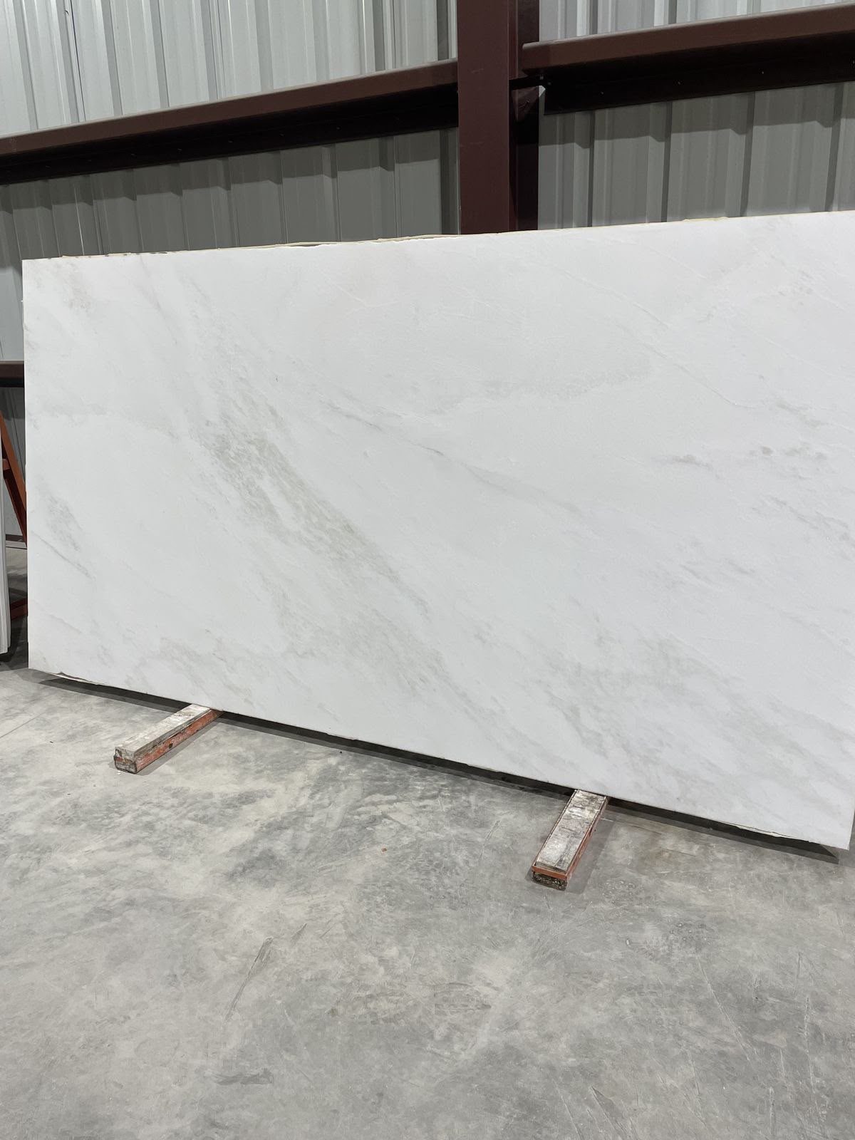 Polished white slab with light grey veins standing in a warehouse