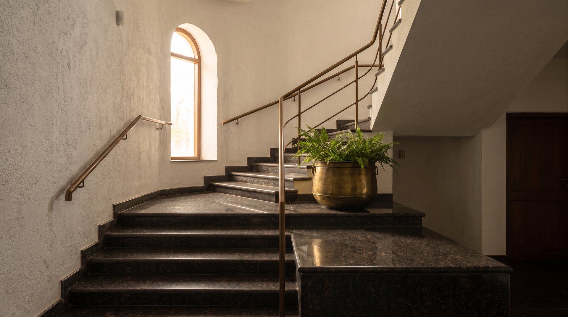 Concept: interior staircase in polished dark granite with a bronze handrail